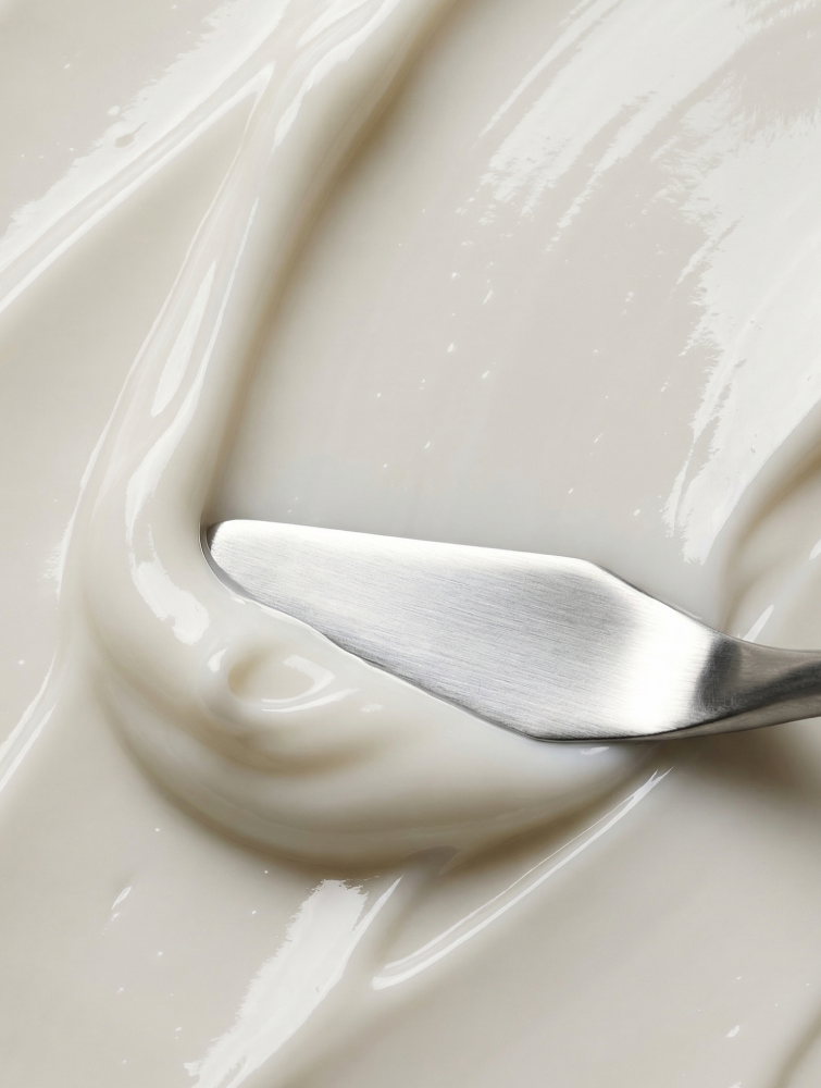 Macro view of Dr. Marnie facial serum texture being spread with a spatula — rich, hydrating clinical formulation.
