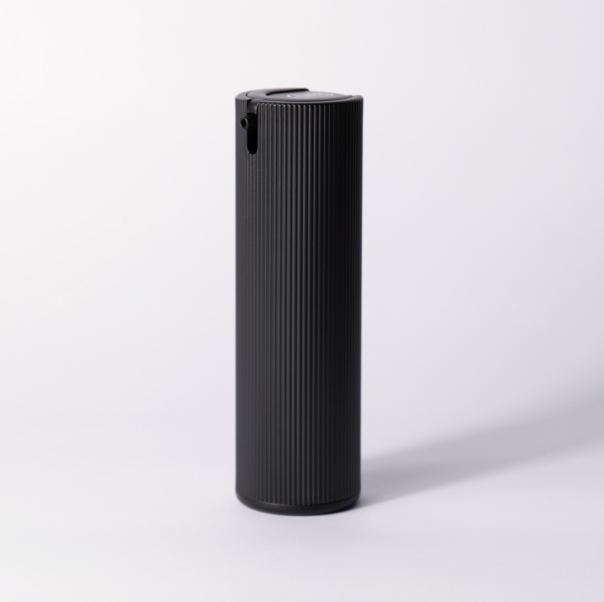 The black ribbed Facial Serum pump bottle standing alone on a soft white studio background.