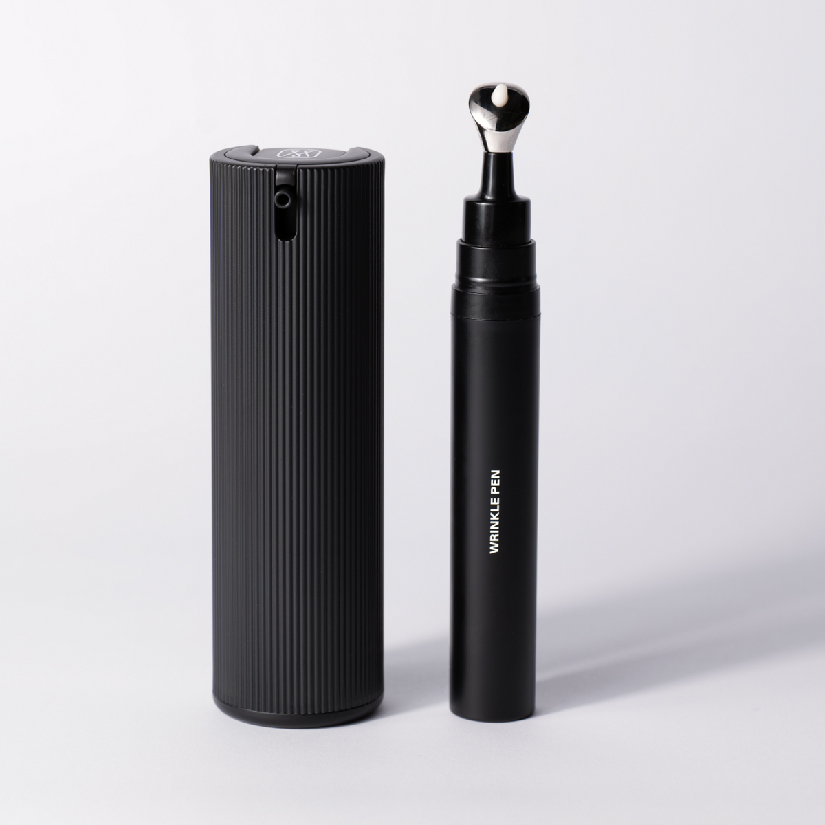Packshot of the Smooth & Firm Duo: the ribbed Facial Serum bottle beside the Wrinkle Pen.