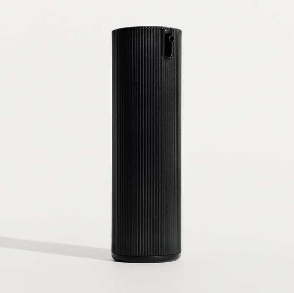 The black ribbed pump bottle standing alone on a plain off-white studio background with a soft cast shadow