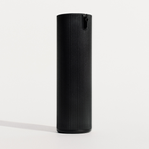 The black ribbed pump bottle standing alone on a plain off-white studio background with a soft cast shadow
