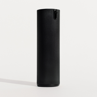 The black ribbed pump bottle standing alone on a plain off-white studio background with a soft cast shadow