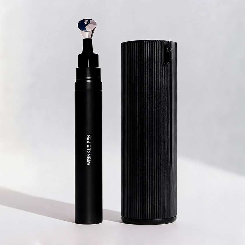 Packshot of the duo on a plain grey background: the black Wrinkle Pen with its metal applicator tip uncapped, standing beside the tall ribbed black Facial Serum bottle