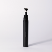The black Wrinkle Pen standing upright with its metal applicator tip on a soft white studio background.