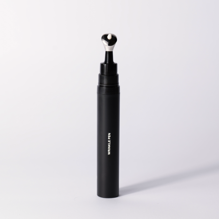 The black Wrinkle Pen standing upright with its metal applicator tip on a soft white studio background.